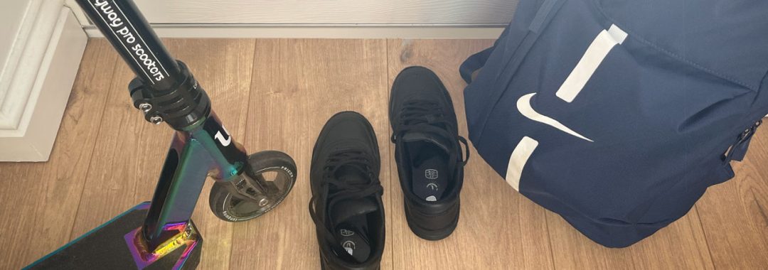 Scooter, school shoes, and school bag leaning against a white composite door.